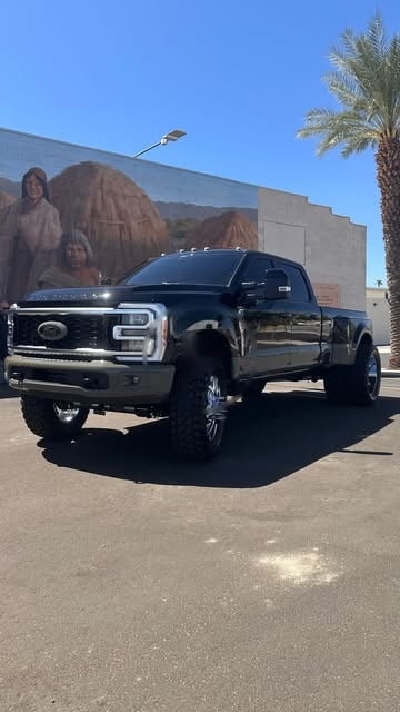 A black Ford F-350 dually parked in front of a mural in Indio